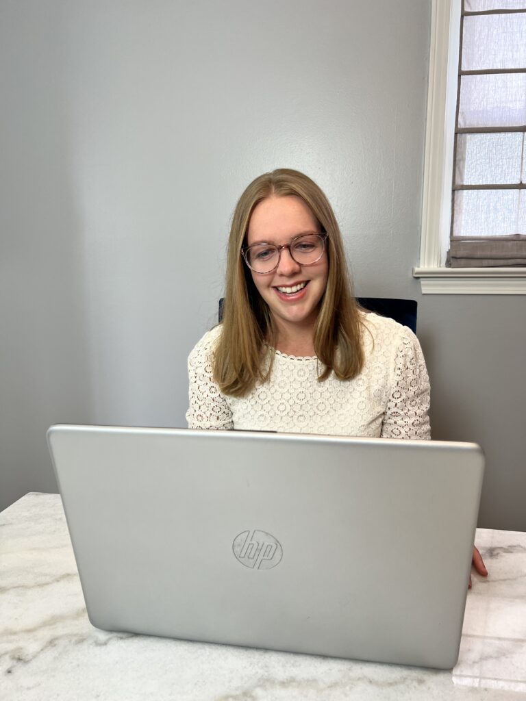 Sarah Robbins of AccentEquip smiling down at laptop screen